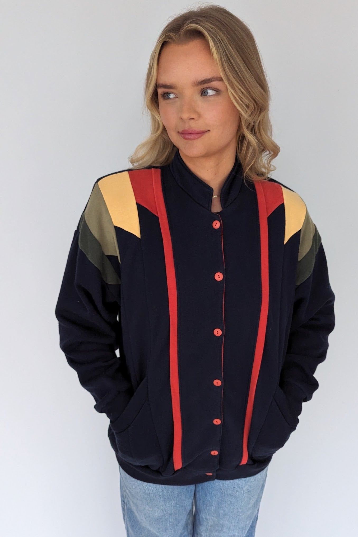 retro jersey cardigan in blue with red, yellow and green panelling done up with red buttons and pockets