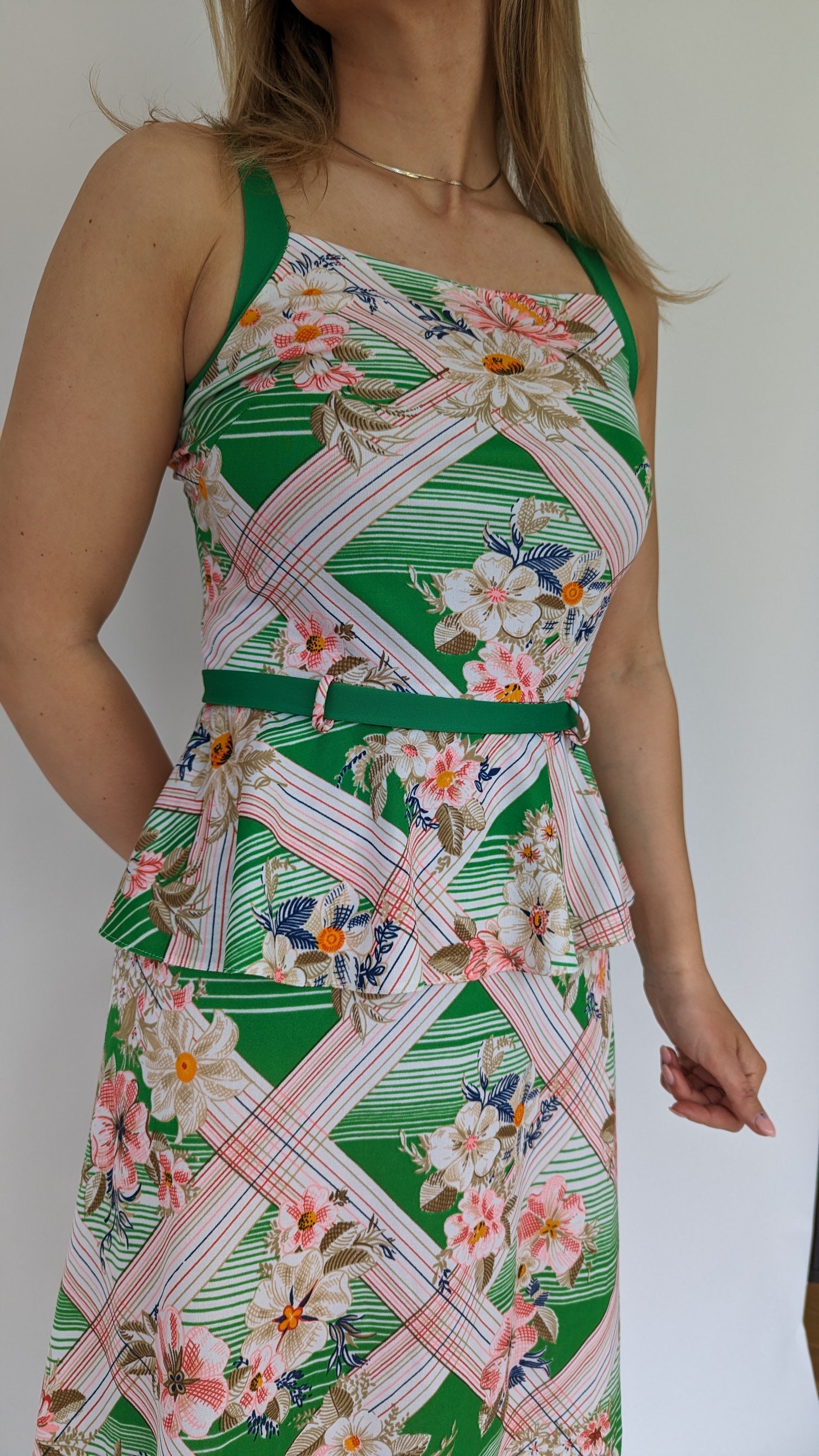 close view of vintage tropical patterned peplum dress with green belt in white, green and pink