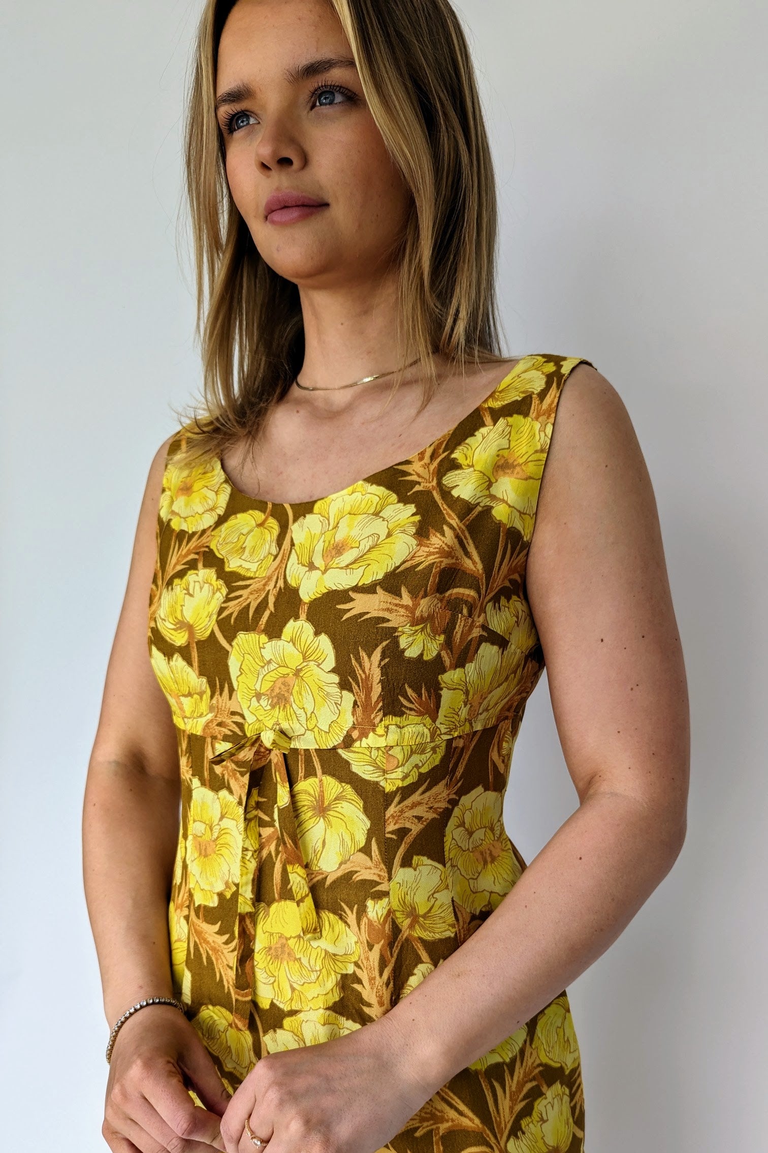 front of 1960s brown and yellow floral shift wiggle dress with empire line showing bow