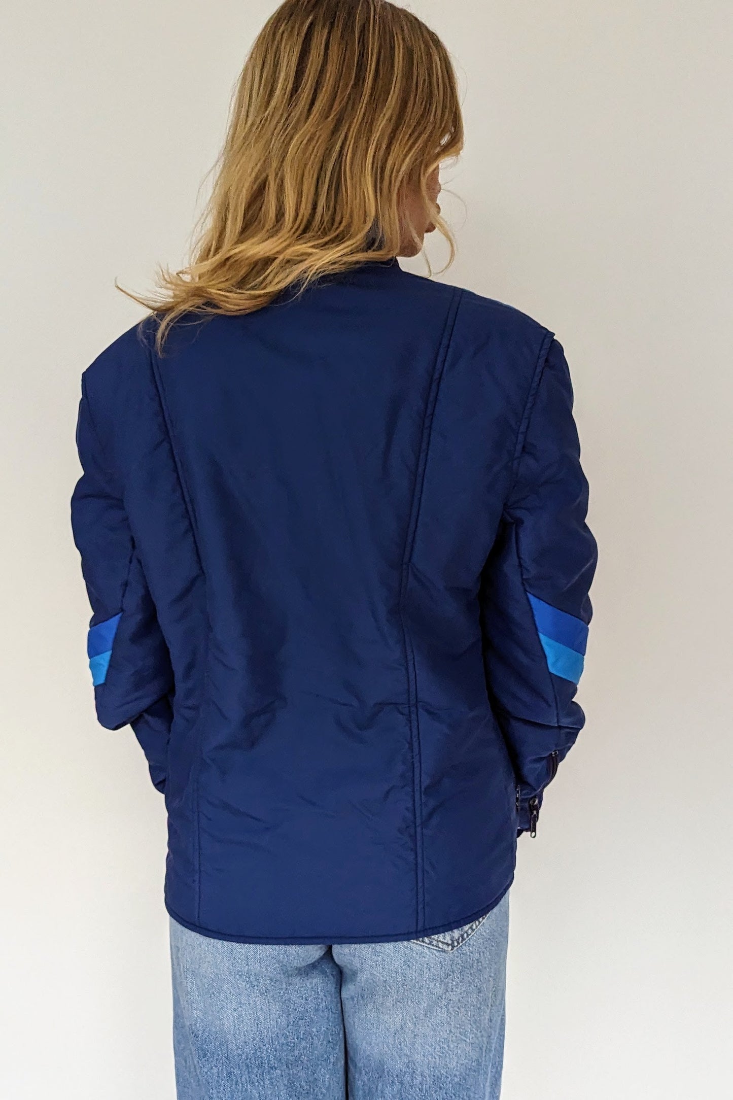 back of vintage blue puffer ski jacket with different tones of blue stripes on front, sleeves and neck