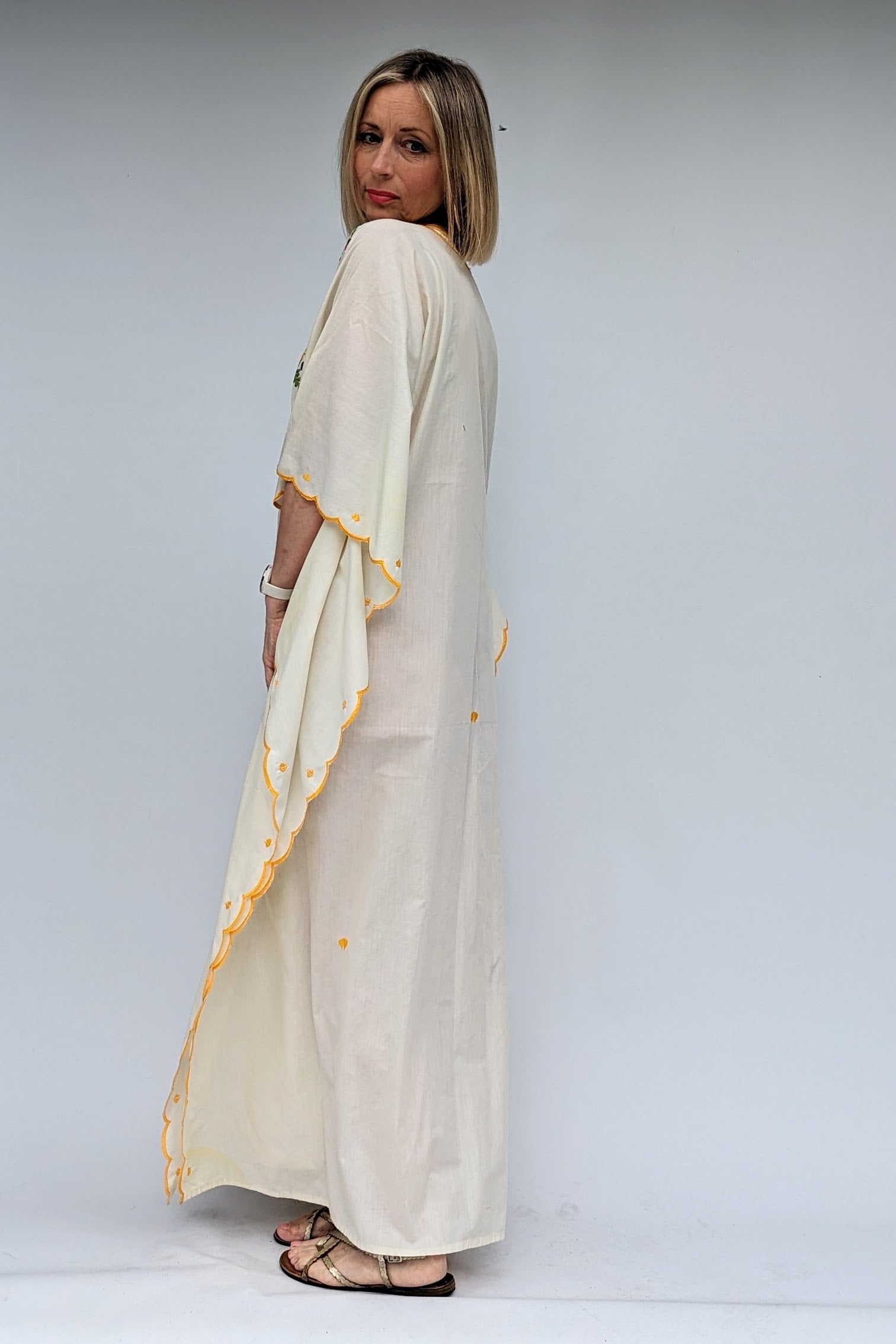 side view of vintage cream kaftan with embroidered flowers in yellow, green, pink and lilac