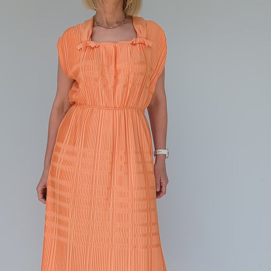 video of vintage pleated peach coloured midi dress from 1960s with square neck and bows