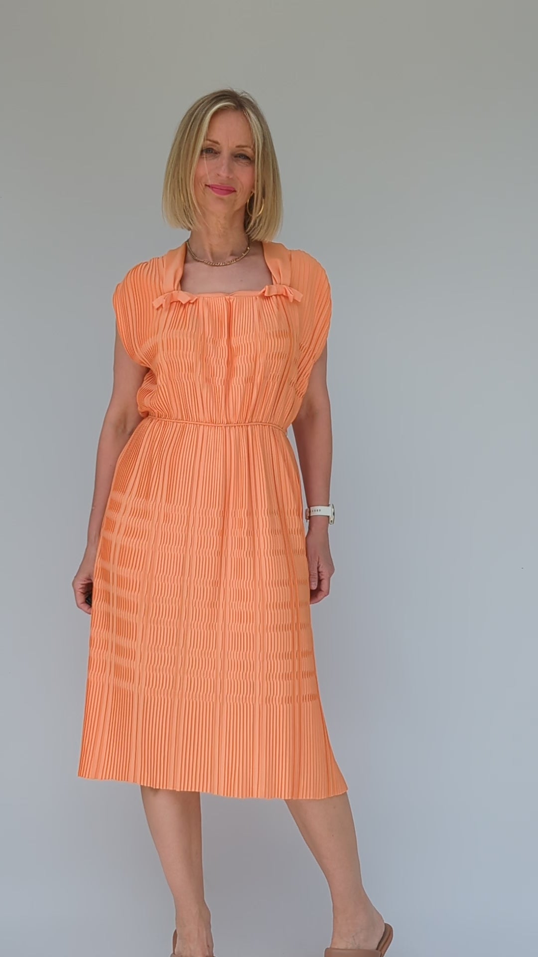 video of vintage pleated peach coloured midi dress from 1960s with square neck and bows