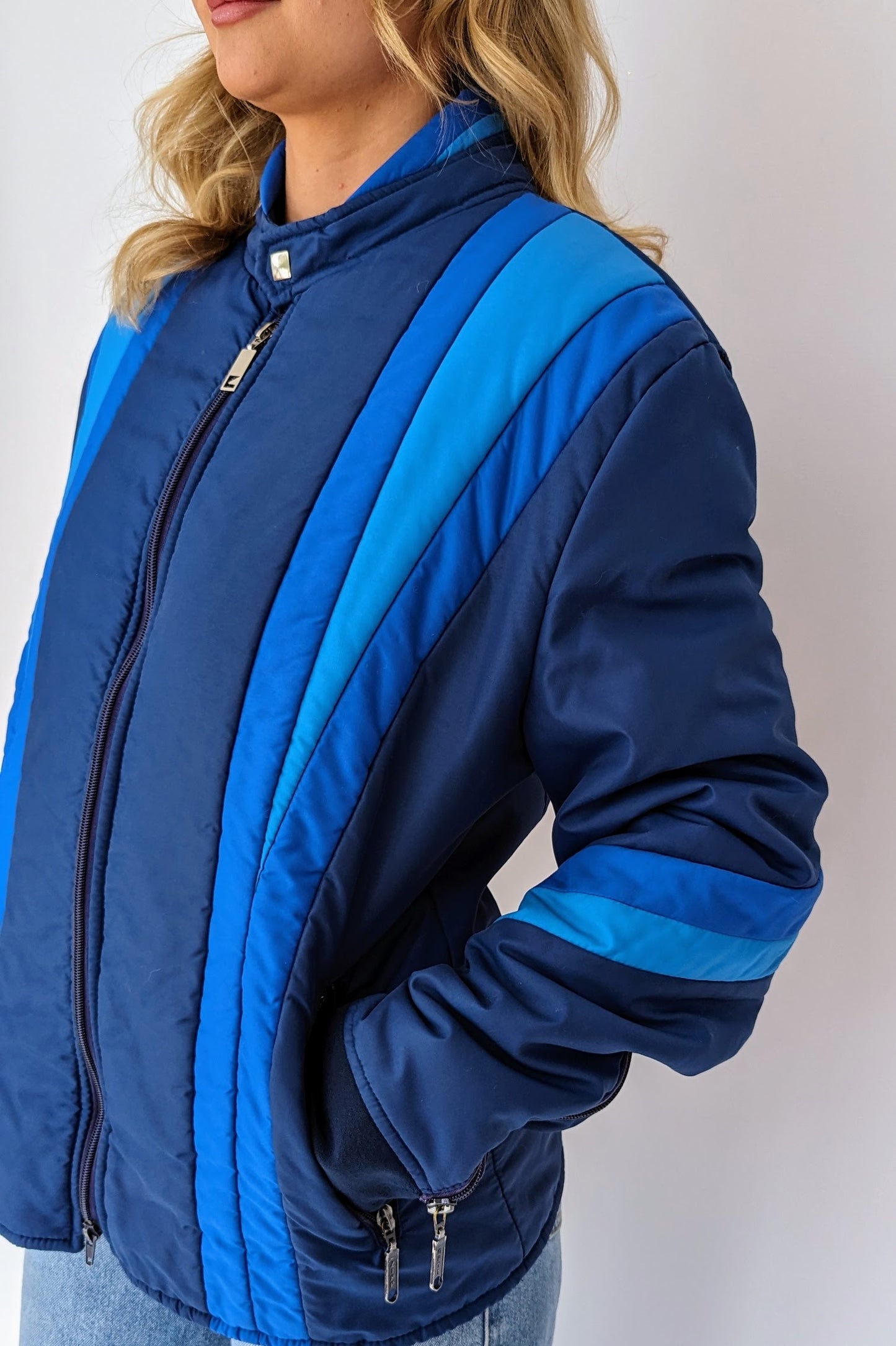 zipped up vintage blue puffer ski jacket with different tones of blue stripes on front, sleeves and neck